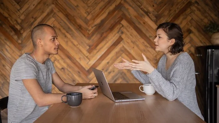 Two people talking and working on a laptop at a drug and alcohol rehab clinic in Devon