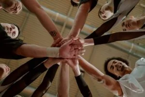 Group of people in a circle with their hands in the middle touching