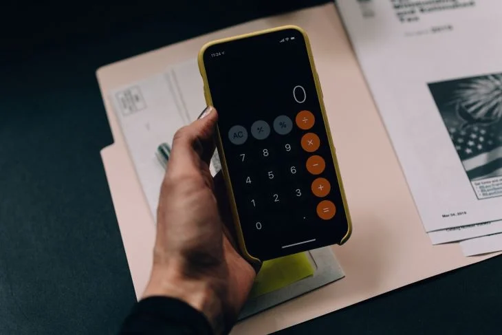 A phone calculator held above some documents