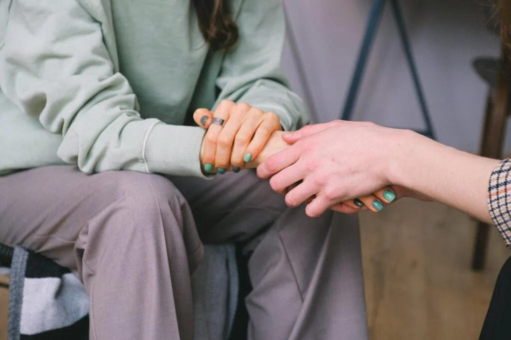 Two women holding hands supportively