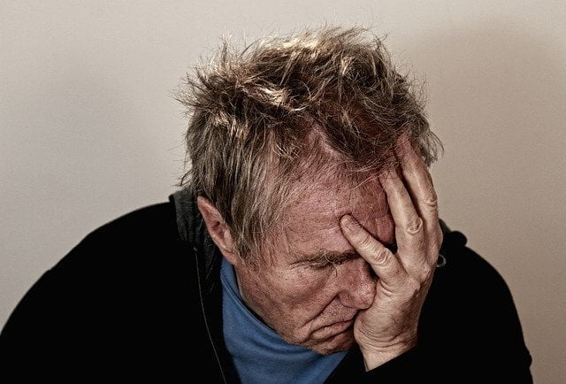 Older man holding his head and experiencing withdrawal from Lortab addiction