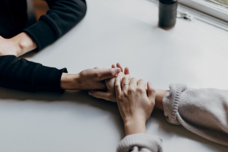 Friends holding hands and talking about the benefits of Kintsugi and Wabi Sabi for mental health