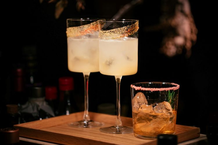 Three mocktails with garnishes on a wooden board